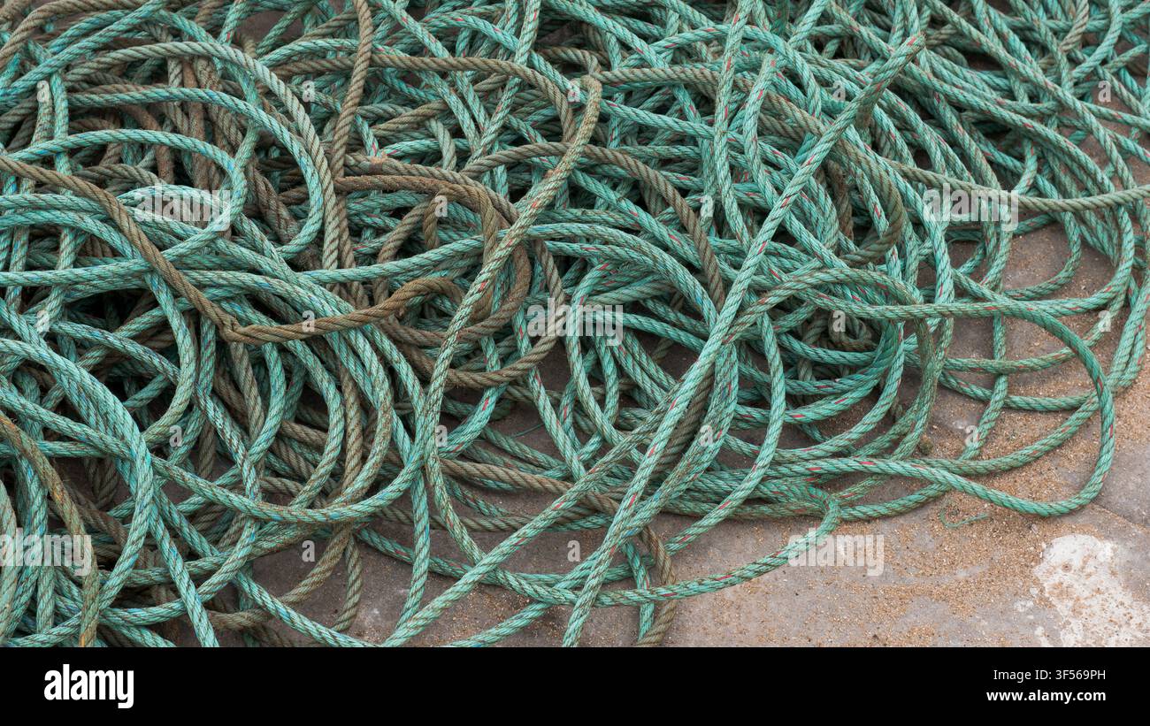 Corde de pêche turquoise enroulée empilée sur un quai en béton, texture maritime abstraite Banque D'Images