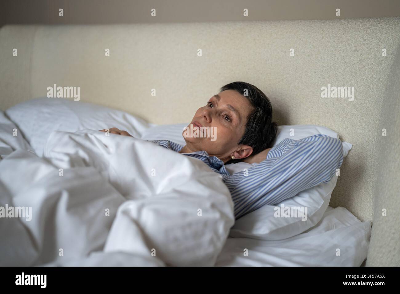 Malheureuse femme aînée réfléchie couchée au lit le matin à la maison avec une expression épuisée perdue. Banque D'Images