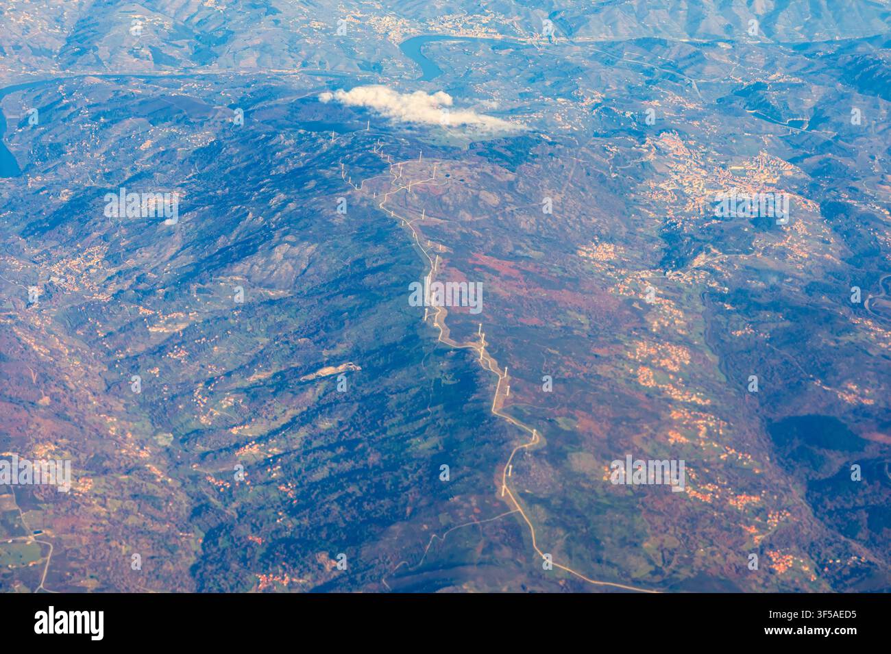 Une vue aérienne révèle une autoroute de montagne sinueuse traversant de vastes crêtes boisées et des hameaux dispersés à travers un paysage européen accidenté Banque D'Images