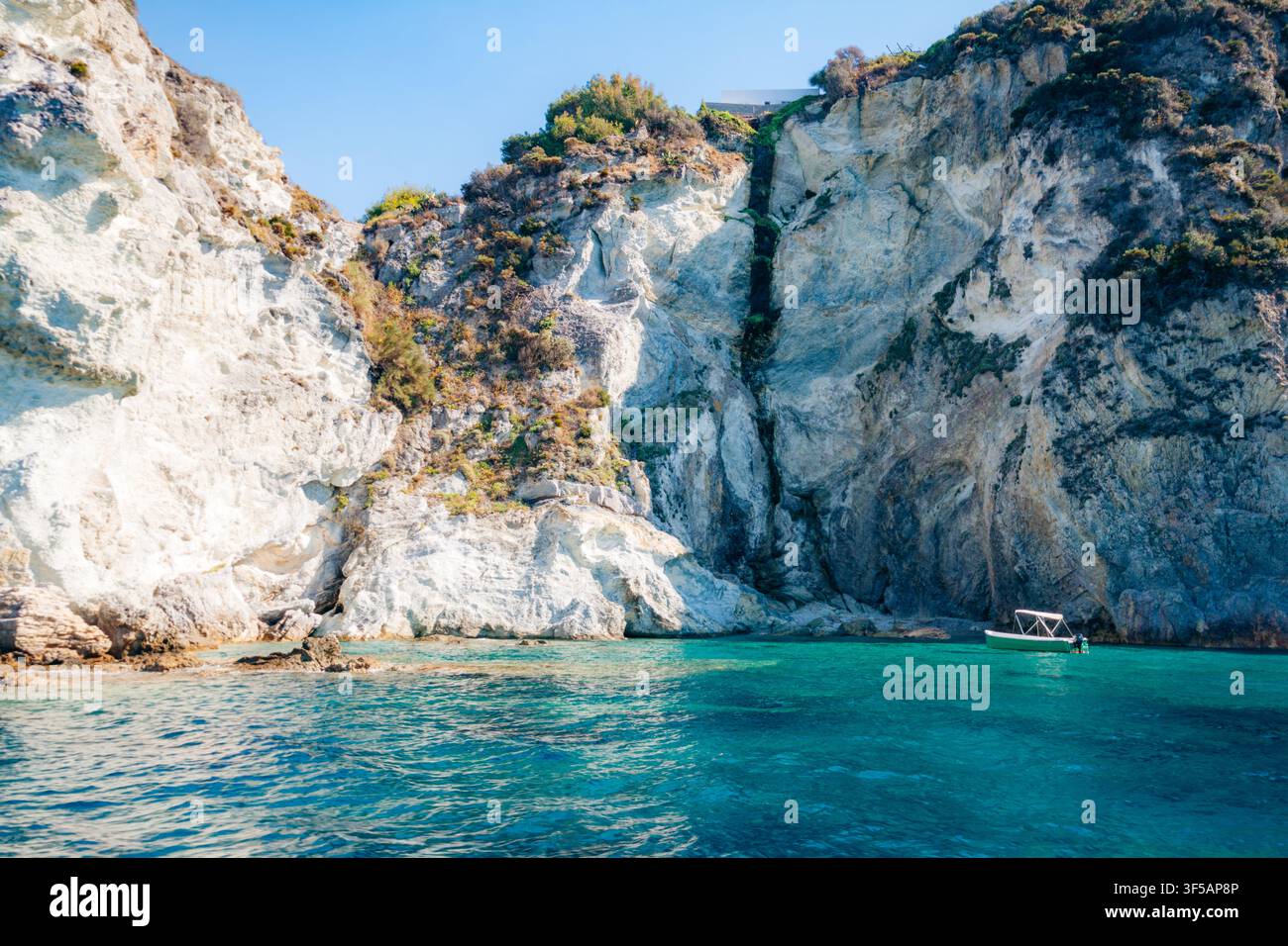 Petit bateau touristique navigue près des impressionnantes falaises de calcaire blanc de l'île de Ponza en Italie. Banque D'Images
