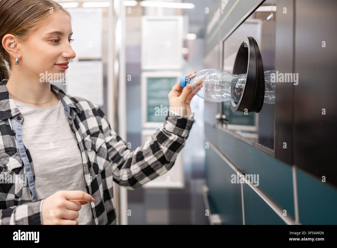 Fille recyclant des bouteilles en plastique vides dans une machine au supermarché Banque D'Images