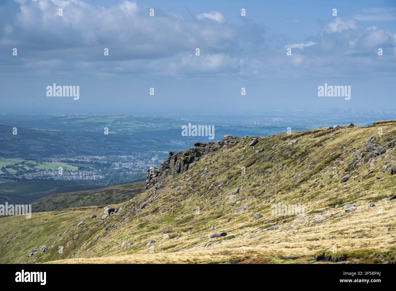 Une vue panoramique élevée depuis Higher Shelf Stones surplombe la ville de Glossop, avec la ligne d'horizon de Manchester visible tout à droite Banque D'Images