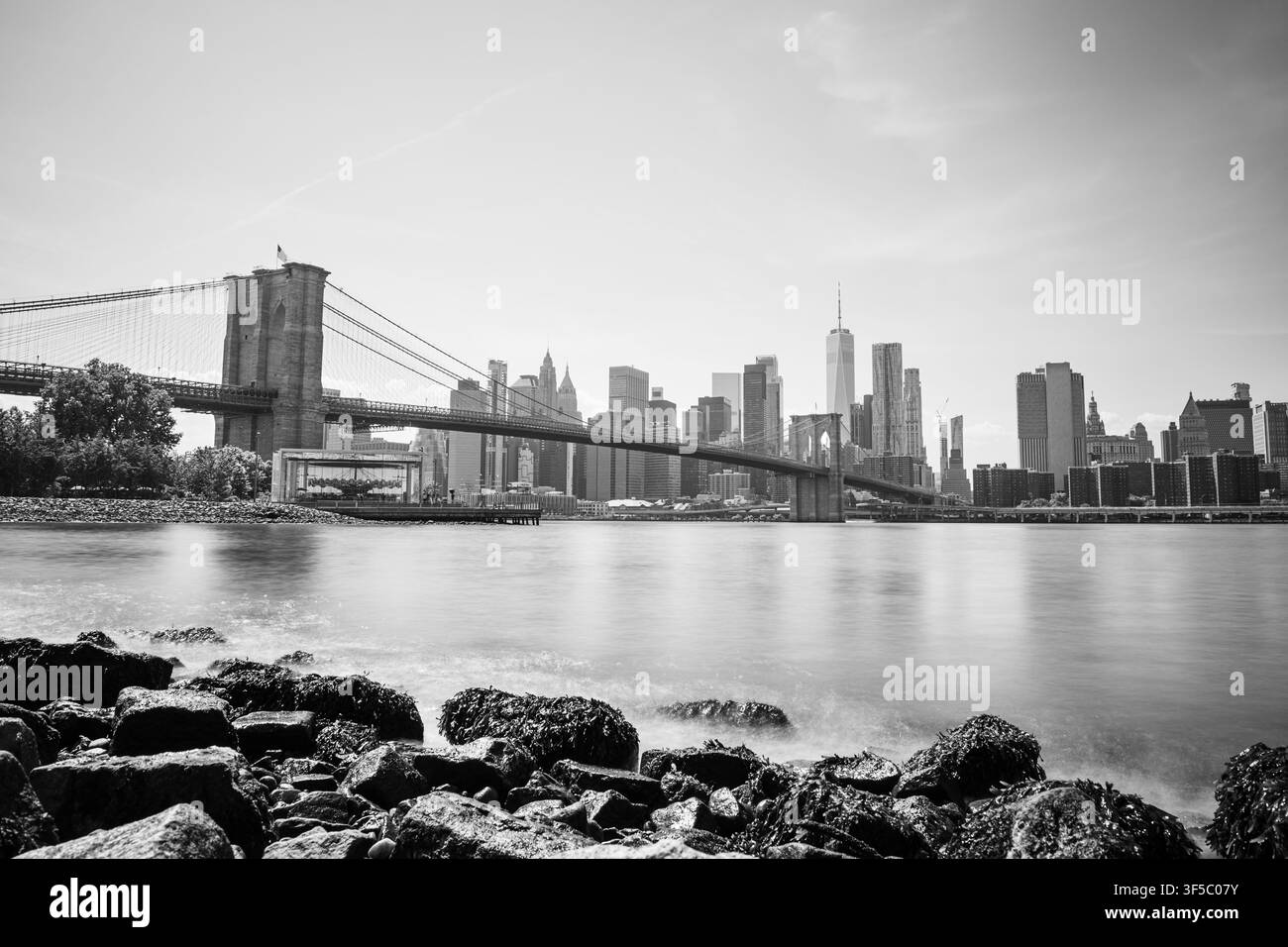 Photographie à longue exposition du pont emblématique de Brooklyn enjambant l'East River avec la skyline de Lower Manhattan en arrière-plan. Capturé depuis Brook Banque D'Images