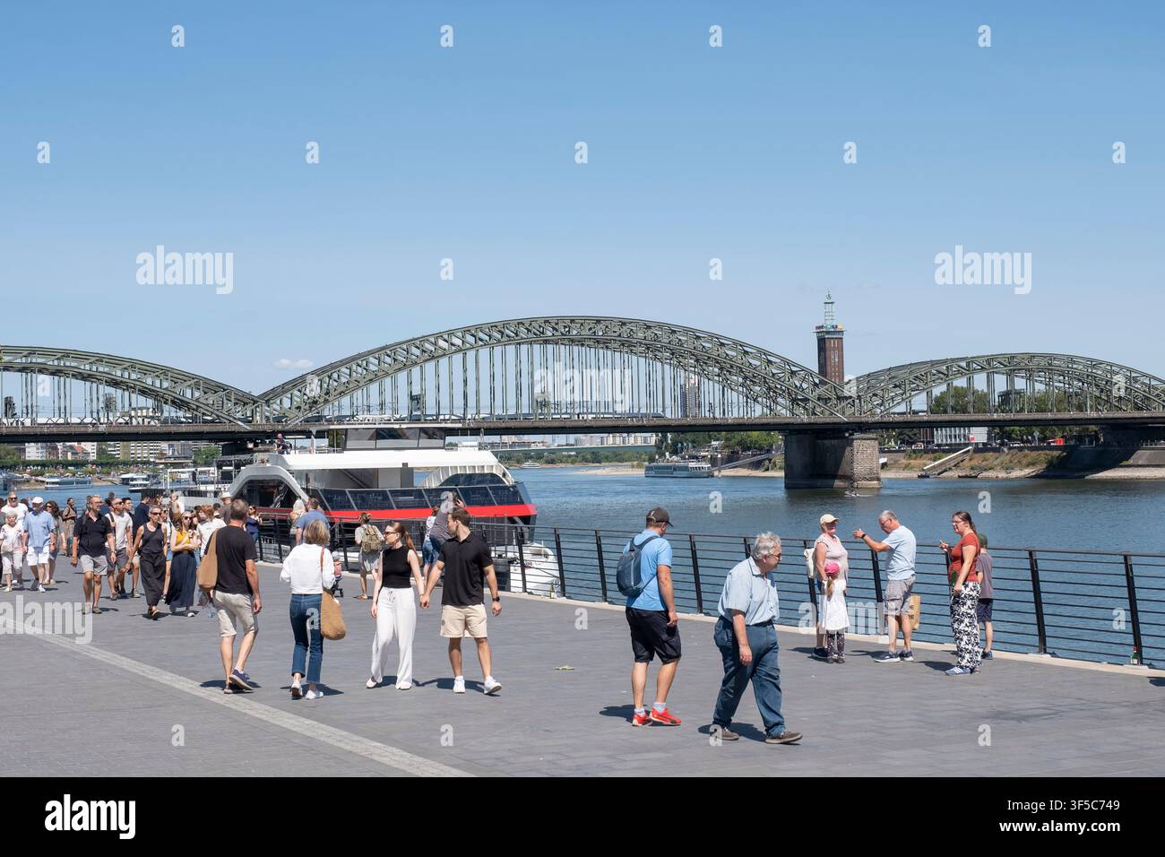 De nombreux passants et touristes se promènent par temps ensoleillé d'été sur la promenade riveraine du Rheingarten à Cologne. En arrière-plan s'étend Banque D'Images