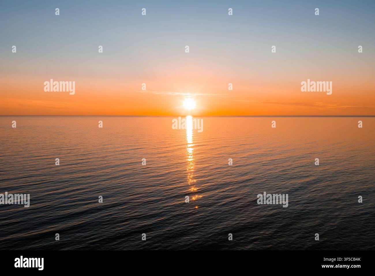 Soleil bas sur la mer Baltique près de Ventspils avec un chemin de lumière vertical Banque D'Images