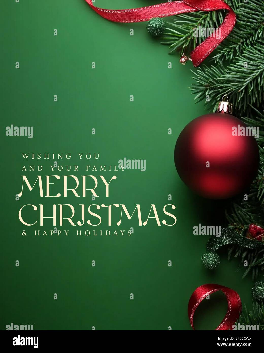 Fond vert avec ornement de Noël rouge et branches de pin. Un ruban rouge s'enroule à côté d'une boule brillante. Le texte dit : "Wishing you" Banque D'Images
