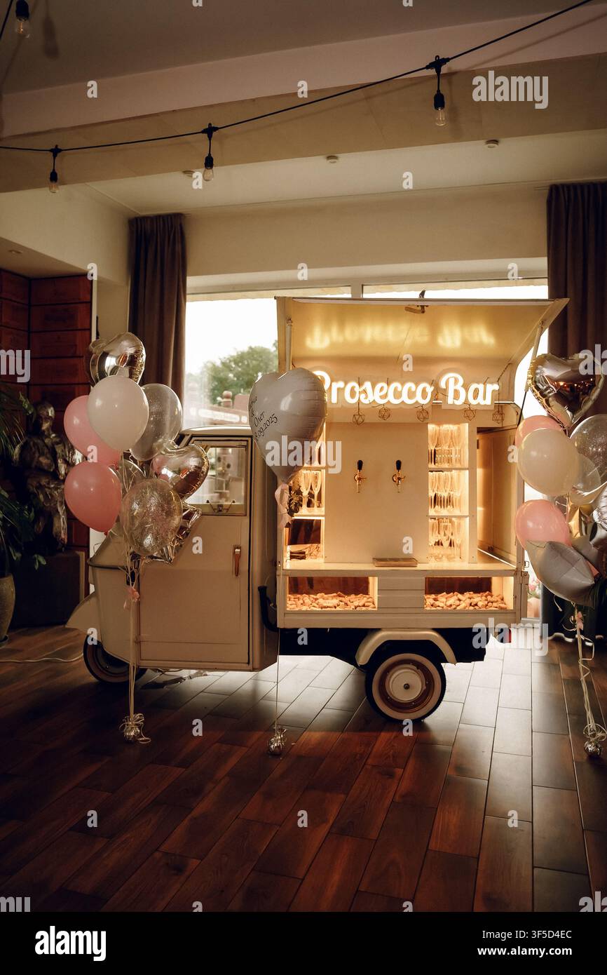 Bar à champagne mobile dans un petit camion vintage décoré de ballons, parfait pour les mariages, les fêtes et le service de boissons pour événements haut de gamme, configuration de chariot à champagne pour les fêtes, célébrations Banque D'Images