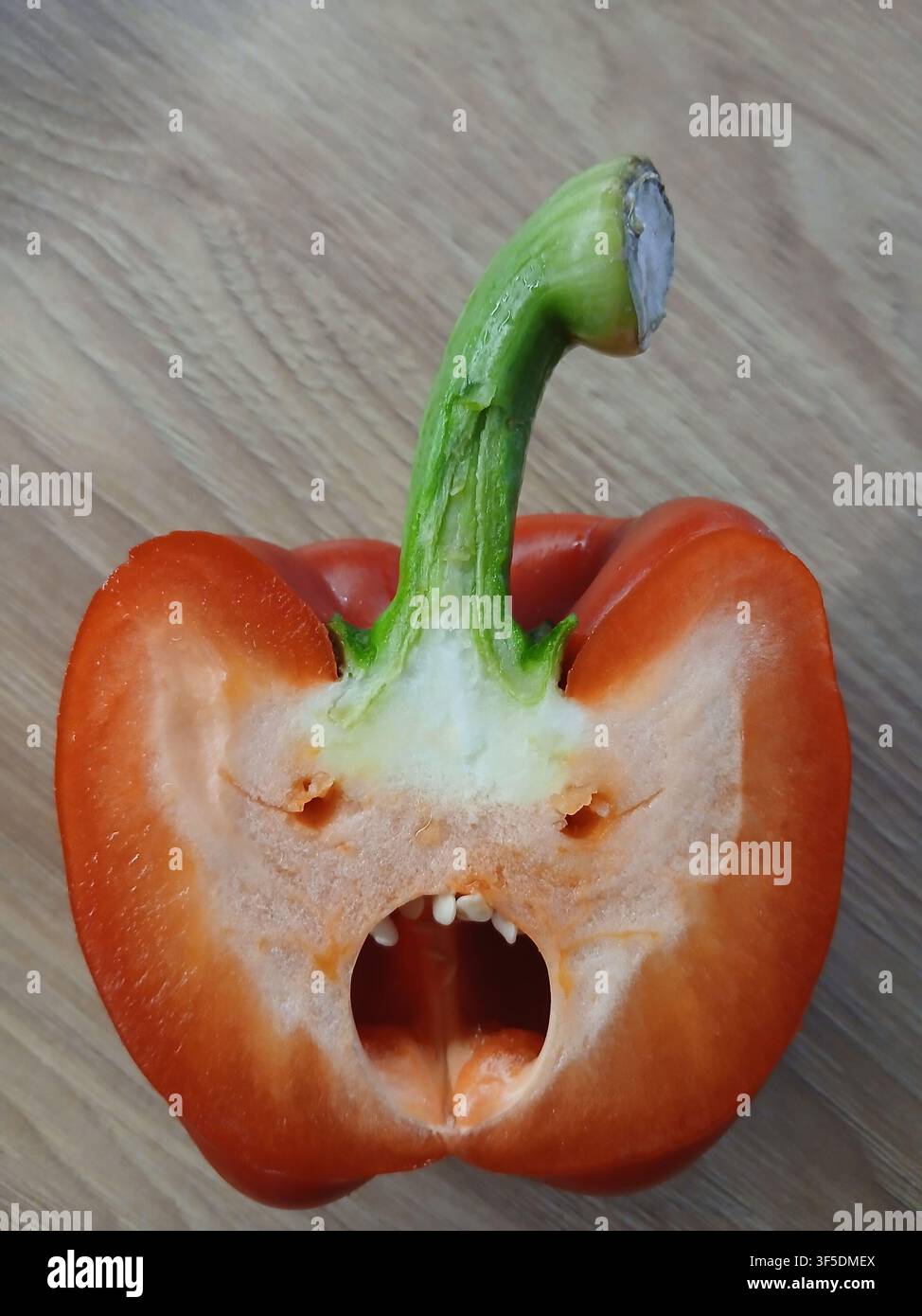 Une coupe drôle d'un poivron rouge frais qui ressemble à un visage de monstre hurlant, montrant un exemple amusant de paréidolie - Image de stock capturée avec un smartphone