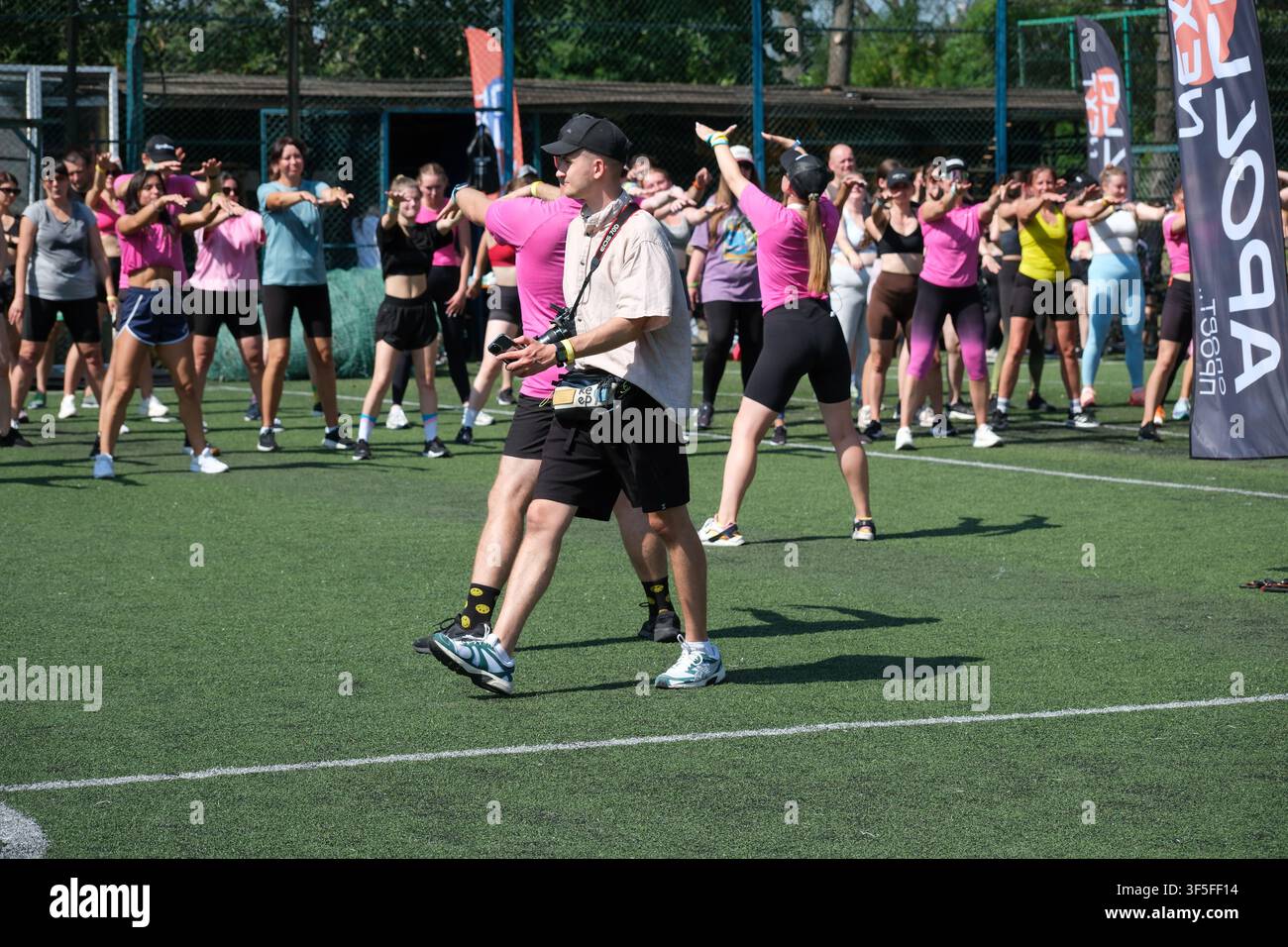 KIEV, UKRAINE - 1ER AOÛT 2026 : Un photographe traverse le champ tandis que des participants effectuent des exercices synchronisés lors d'une grande communauté en plein air Banque D'Images
