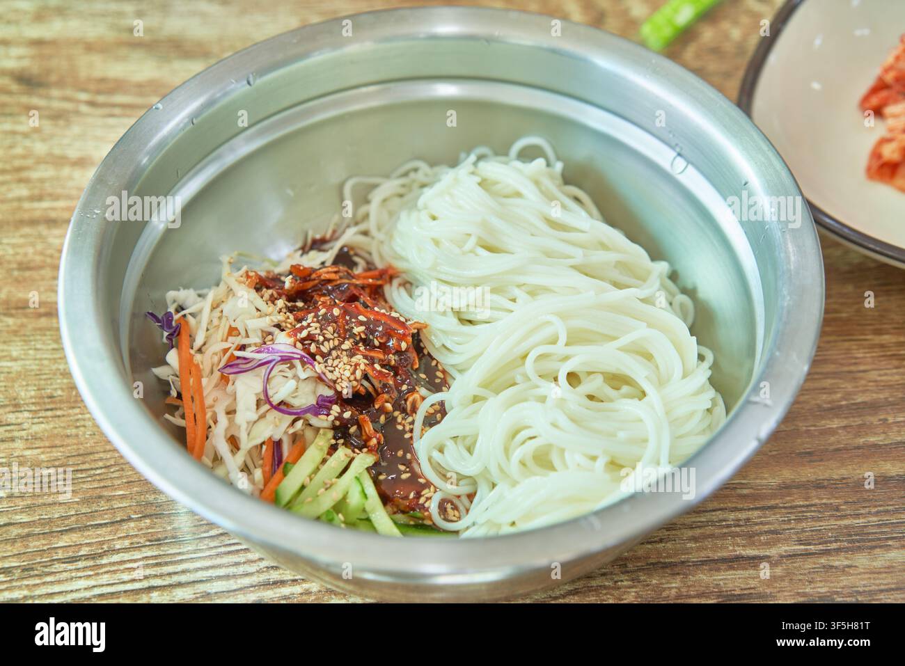 Bibim guksu, nouilles froides coréennes épicées avec légumes et sauce au piment, une collation de rue populaire que l'on trouve sur les marchés coréens. Banque D'Images
