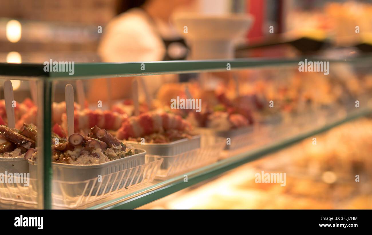 Portions à emporter de salade de pieuvre et brochettes de crevettes dans une vitrine en verre éclairée — Concept de street food, repas prêts à consommer et tourisme des fruits de mer Banque D'Images