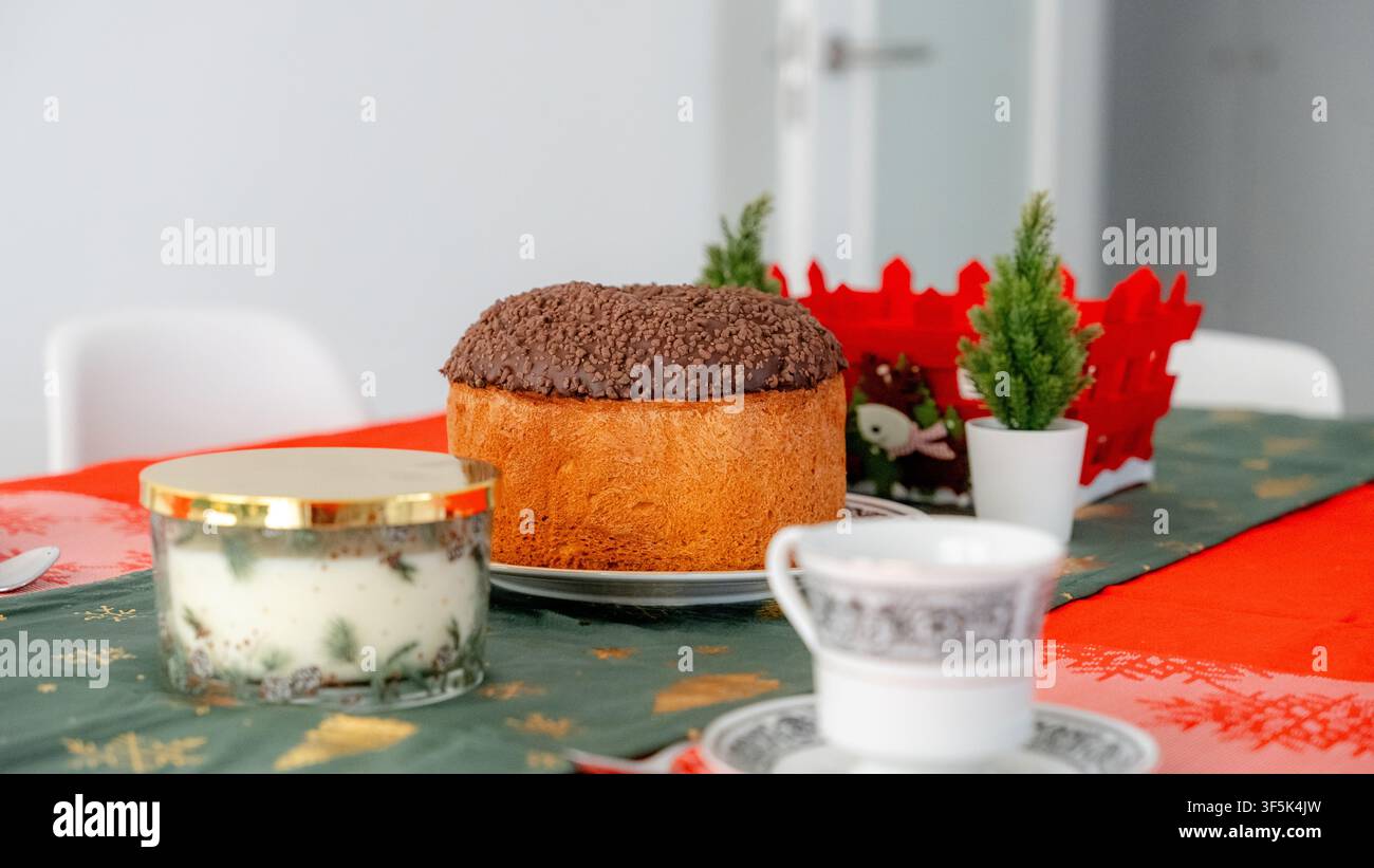 Gâteau panettone et café servis sur une table dressée de manière festive pour un petit-déjeuner du Nouvel An à la maison, avec bougie, décorations de table et indoo douillet Banque D'Images