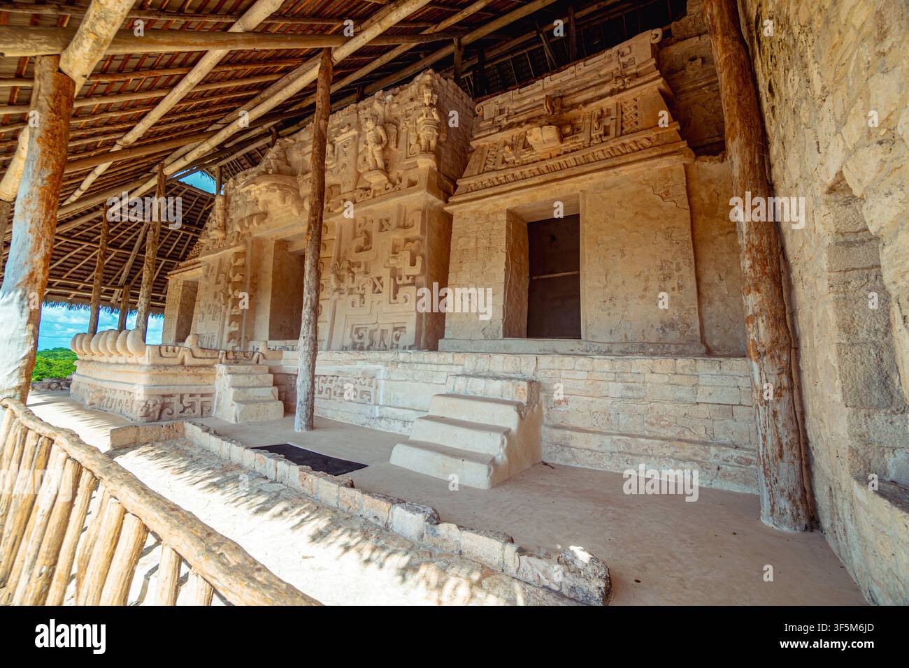 Des sculptures en pierre anciennes ornent les murs érodés du temple. Des poutres en bois protègent le site du soleil et de la pluie. Des marches mènent à des portes sculptées, évoquant un lieu sacré Banque D'Images