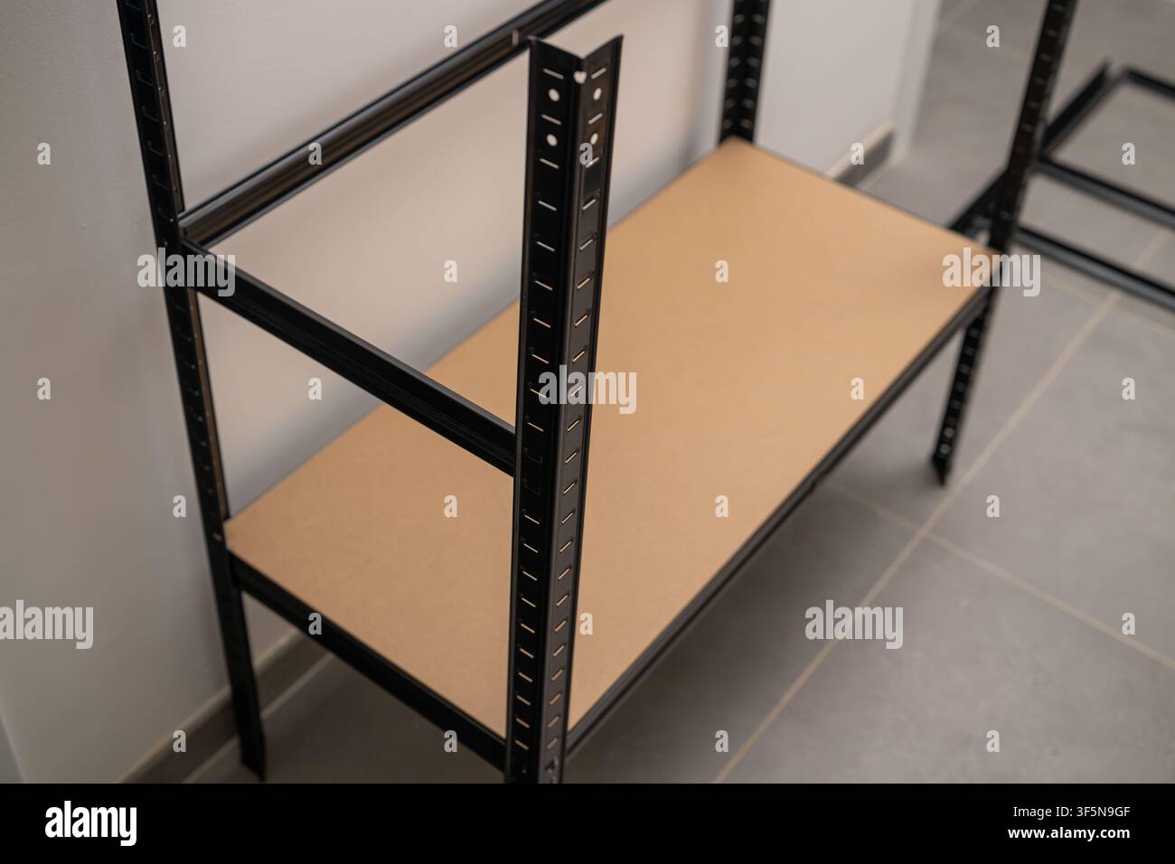 Montage d'une étagère industrielle robuste dotée d'un cadre en métal noir et d'une étagère plate en panneau MDF. Banque D'Images