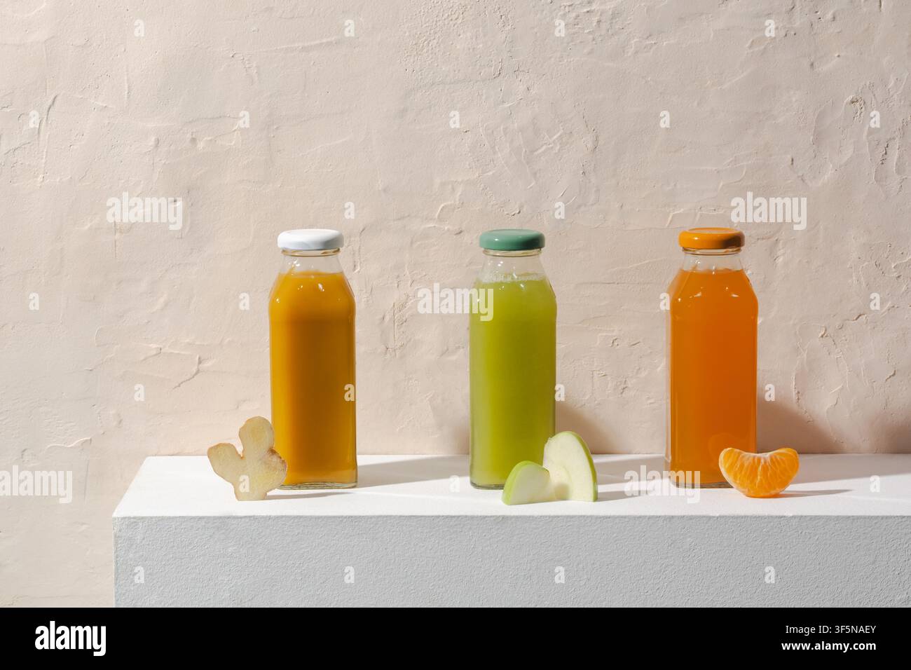 Trois bouteilles de jus vibrant disposées sur une surface blanche avec du frais Banque D'Images