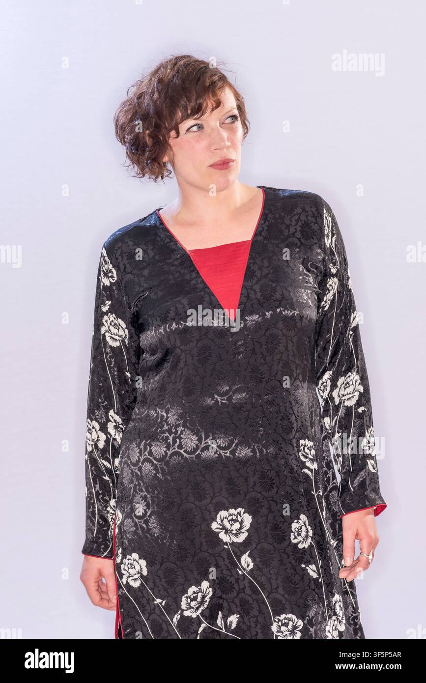 Rachel McCrum est dans un studio portant une robe noire à fleurs blanches, regardant pensivement l'appareil photo. Le fond est clair et simple, mettant l'accent Banque D'Images