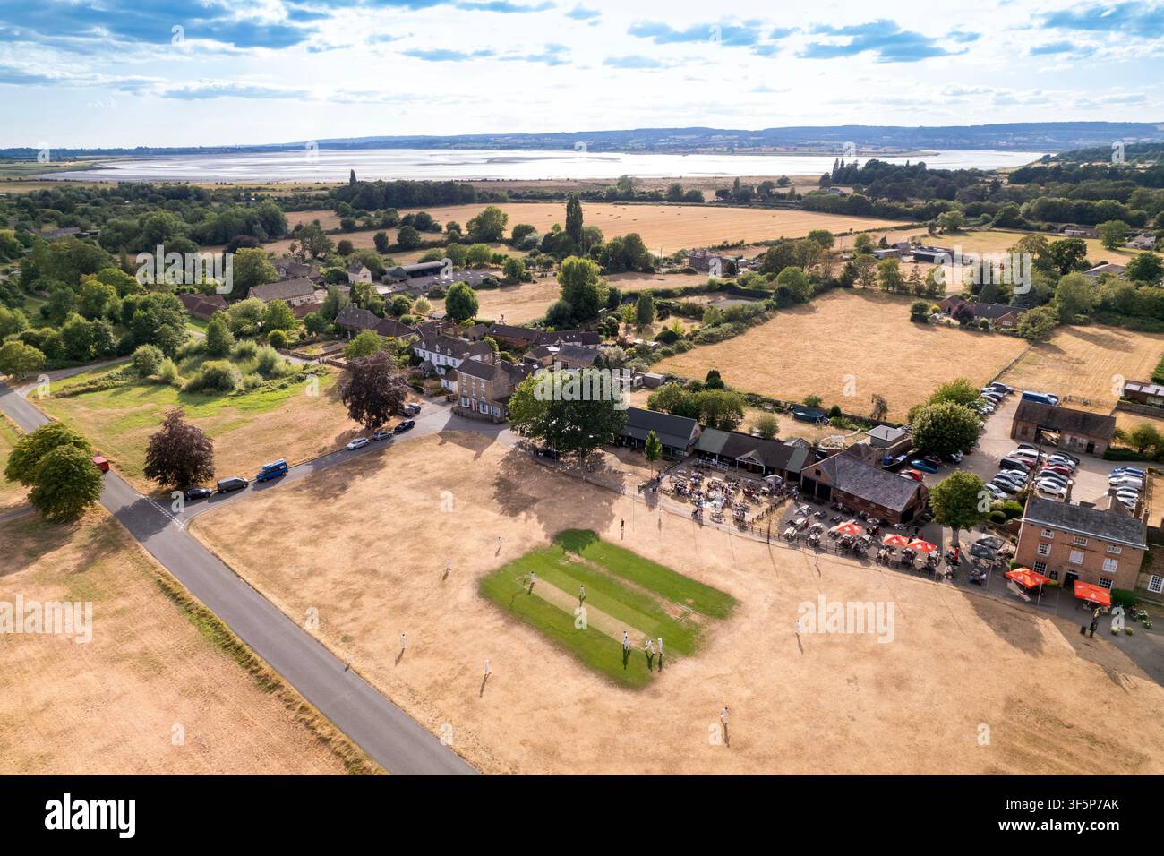 Le contraste frappant entre les wickets de cricket irrigués et le champ extérieur desséché à Frampton on Severn, réputé être l'un des plus longs Banque D'Images