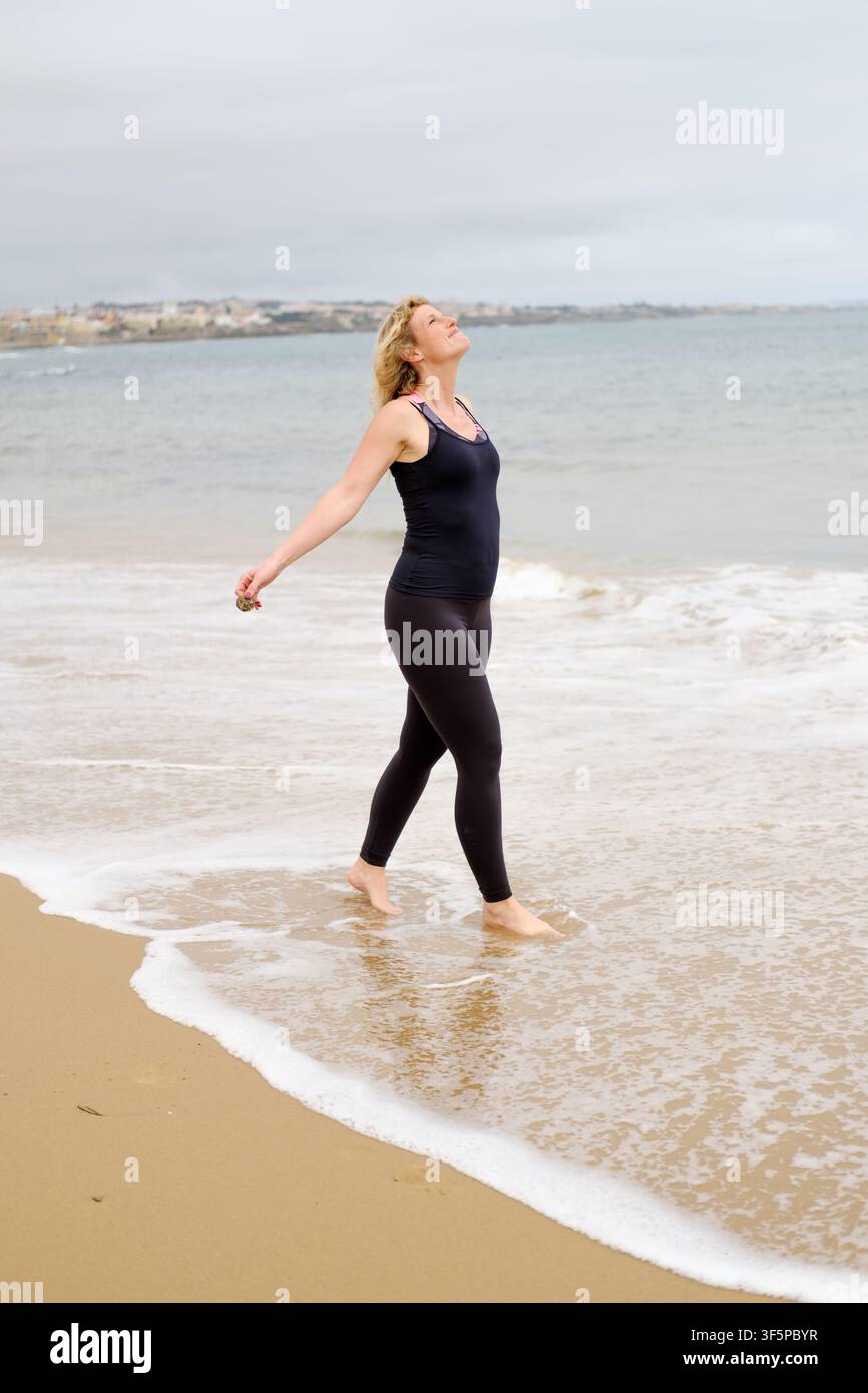 Femme se sent libre et se connecte avec la nature en marchant dans les vagues de l'océan Banque D'Images