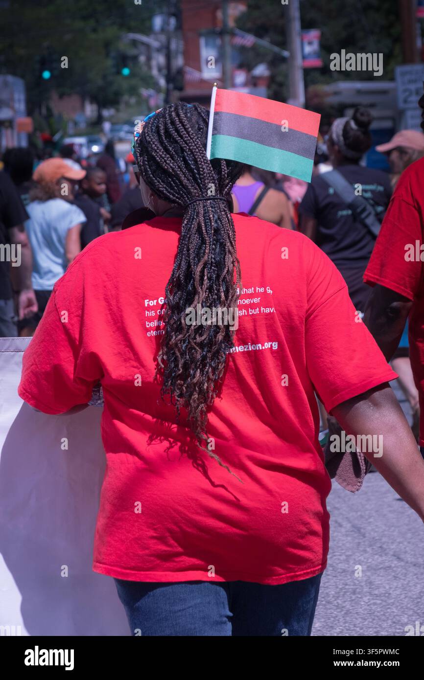 Une femme afro-américaine anonyme défilant lors de la parade de la journée afro-américaine à Nyack avec le drapeau panafricain à trois couleurs. À Nyack, Rockland Cnty. Banque D'Images