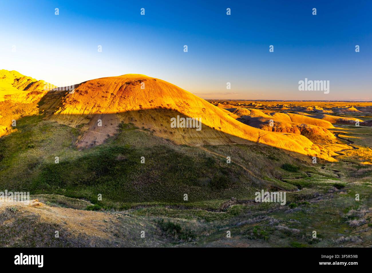 Vue panoramique des formations rocheuses érodées colorées et superposées et de la prairie dorée du parc national des Badlands, Dakota du Sud Banque D'Images