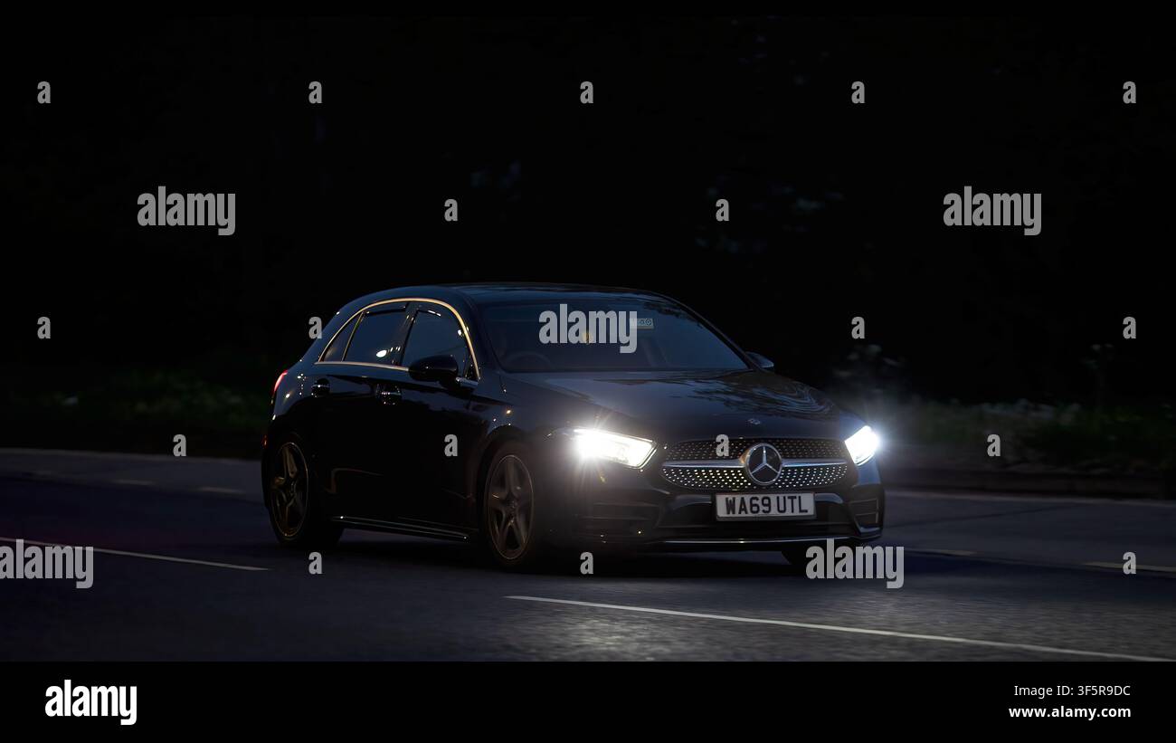 Milton Keynes,Bucks,Royaume-Uni - 29 avr. 2026 : Voiture noire Mercedes-Benz A 180 de 2019 roulant de nuit sur une route britannique Banque D'Images