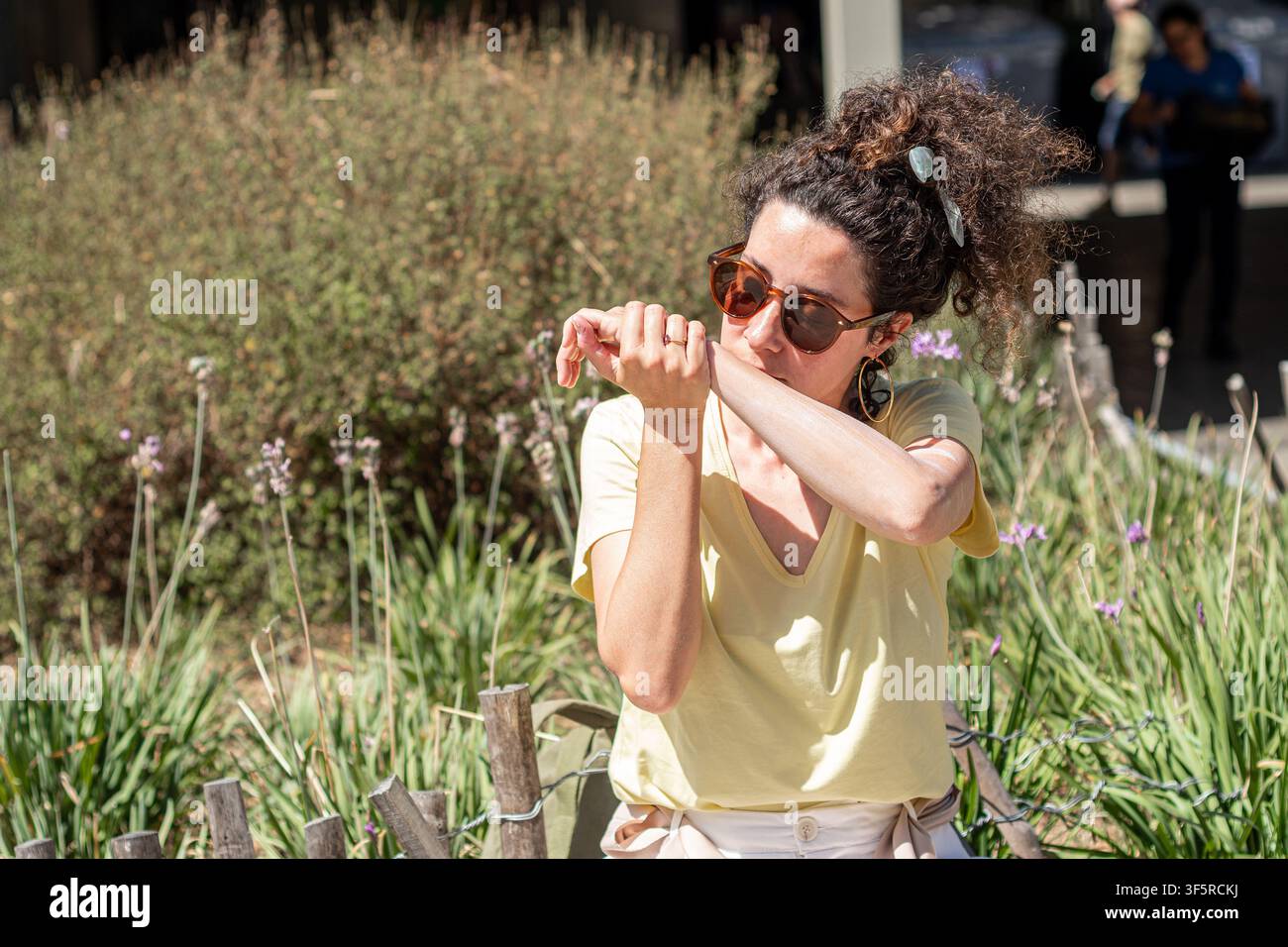 Femme appliquant de la crème solaire sur son bras en plein air pour se protéger du soleil Banque D'Images