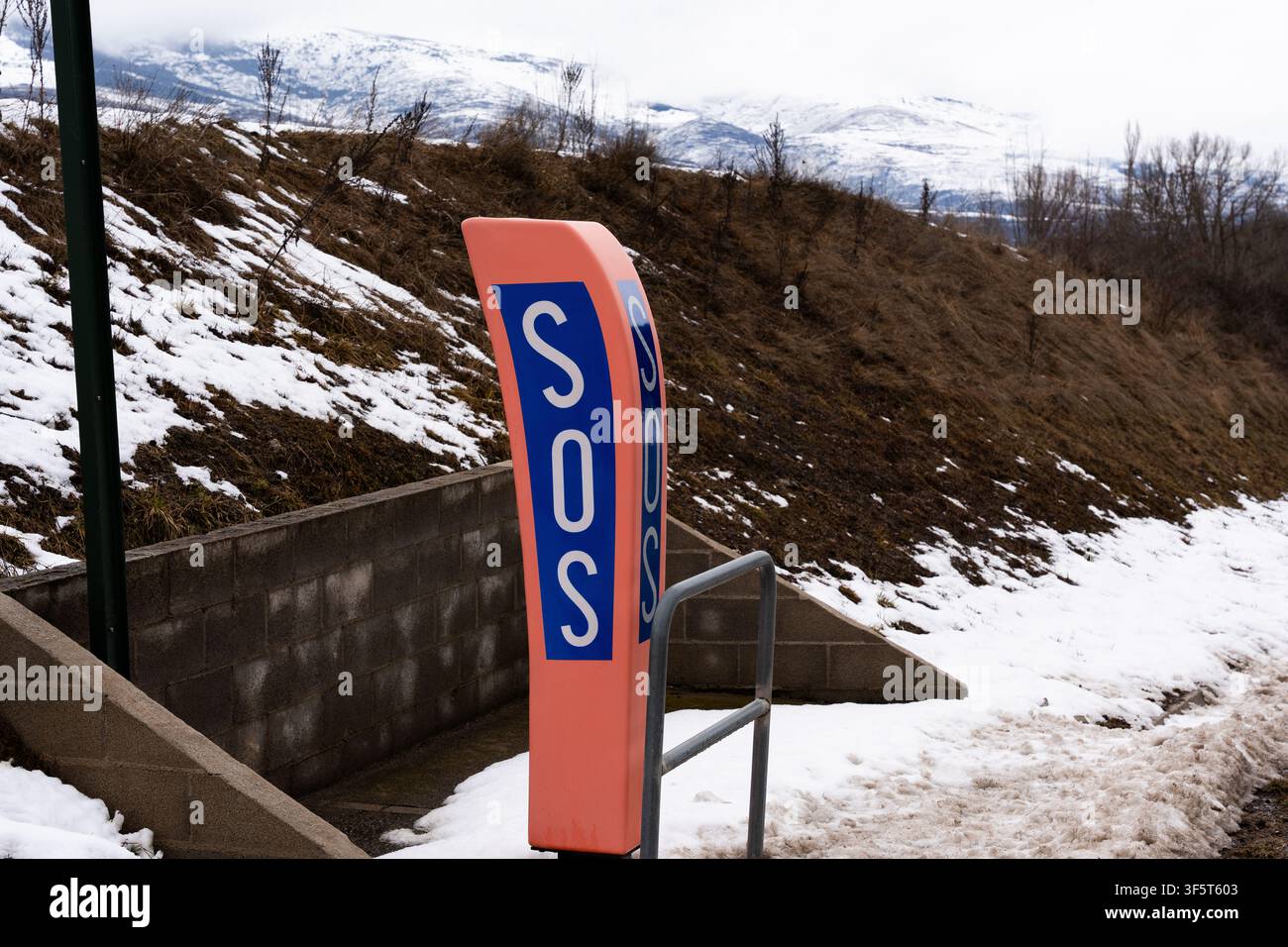 Cabine d'appel d'urgence SOS le long d'une route de montagne enneigée en hiver Banque D'Images