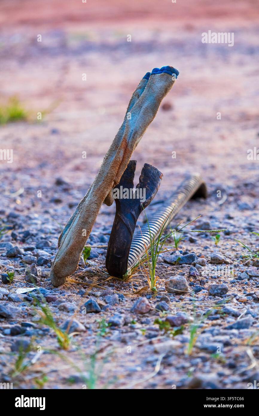 Gant de travail robuste et pied de biche reposant sur un sol de gravier à la tombée du soir Banque D'Images