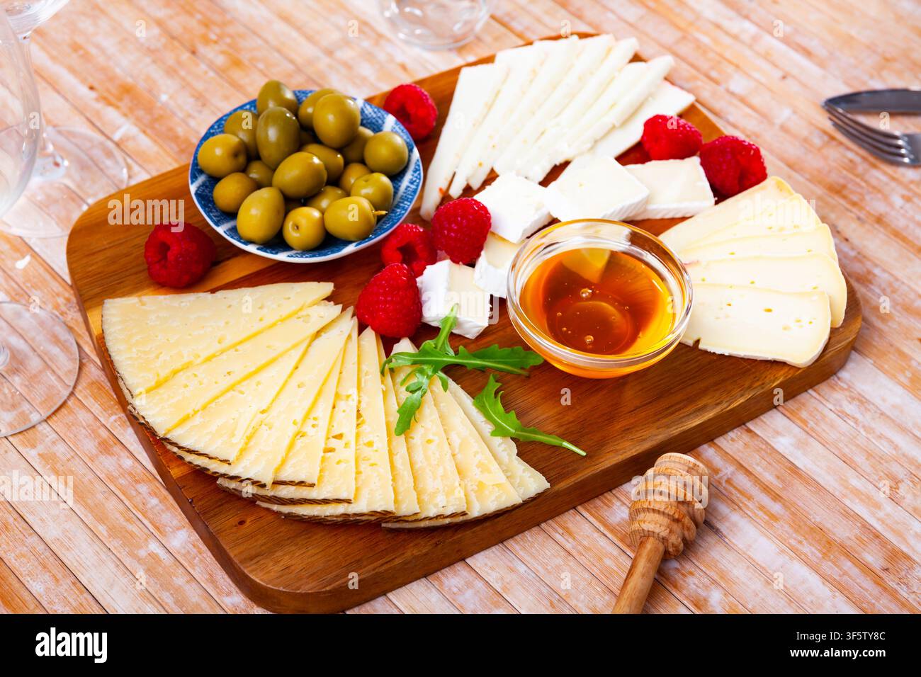 Assiette avec différents types de fromage, framboises et olives Banque D'Images