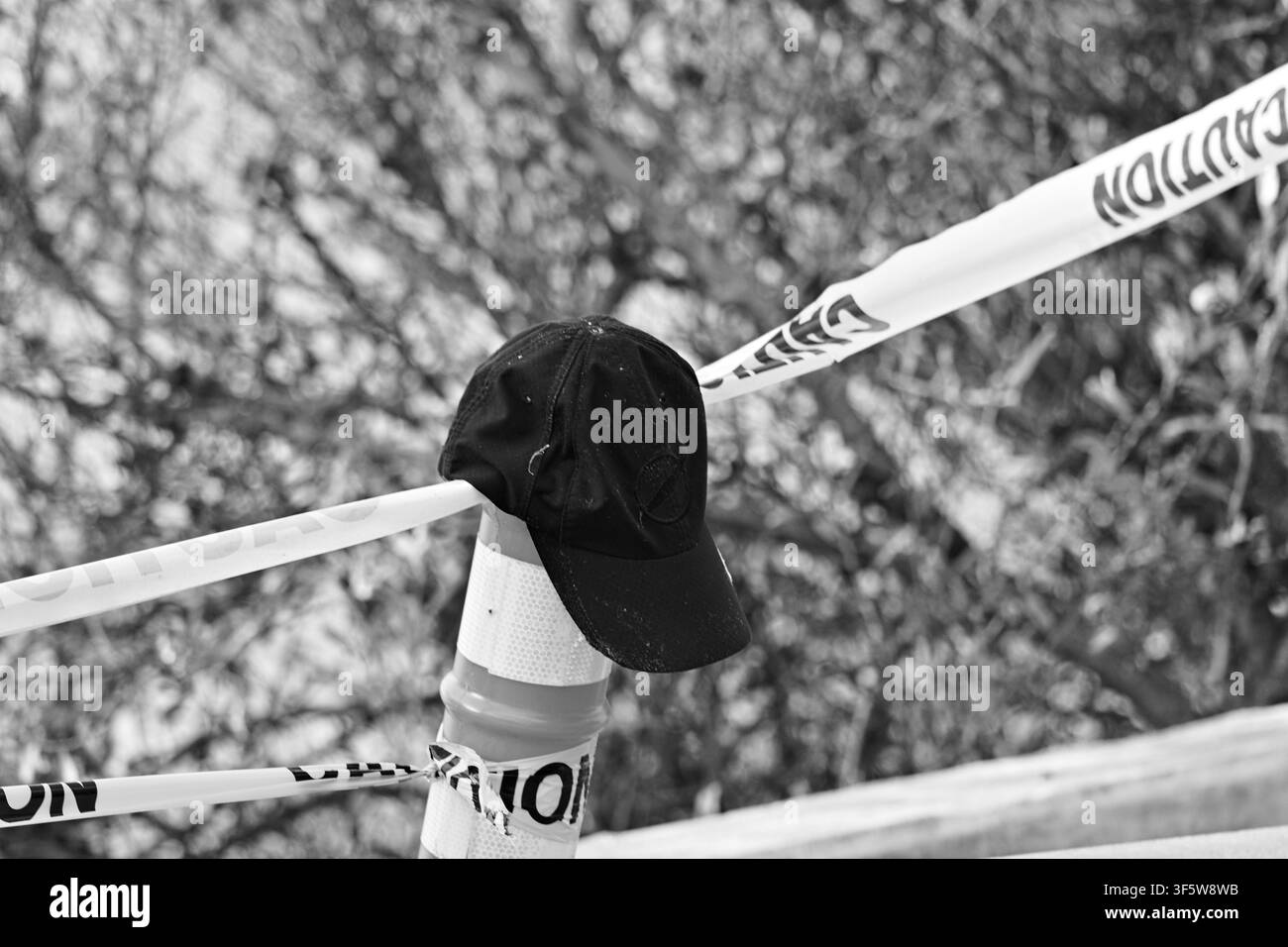 Une casquette noire repose sur un cône de signalisation enveloppé dans du ruban de signalisation à Rat Beach, en Californie, marquant une zone interdite et un problème de sécurité. Banque D'Images