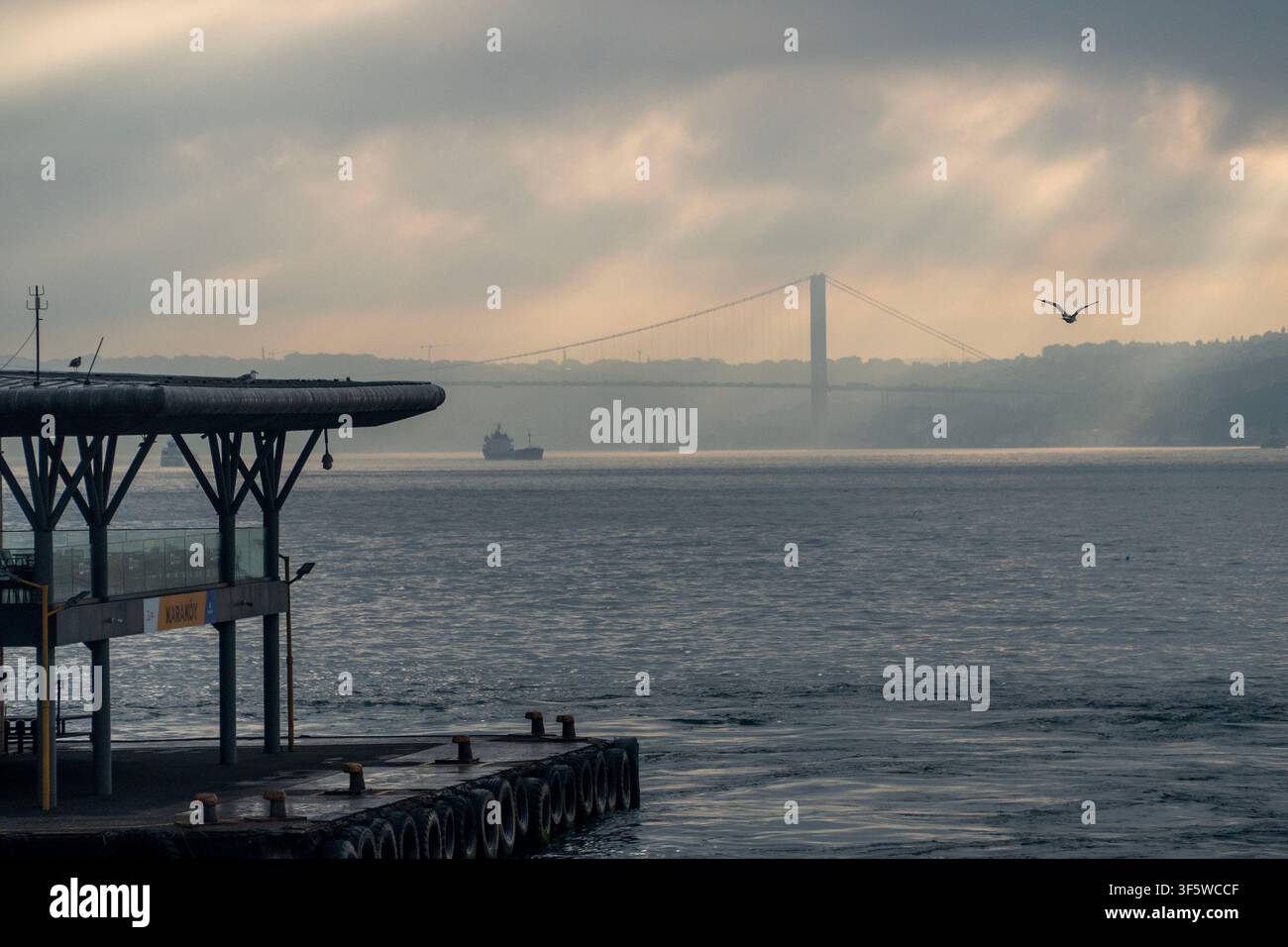 Istanbul, Turquie. 4 août 2026. Un navire de charge navigue alors que le pont du Bosphore enjambe un plan d'eau calme sous un ciel nuageux à Istanbul, Turquie. (Crédit image : © Moe Zoyari/ZUMA Press Wire) USAGE ÉDITORIAL SEULMENT ! Pas pour un USAGE COMMERCIAL ! Banque D'Images