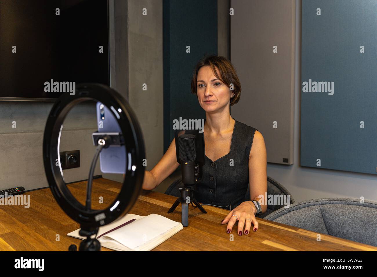 Créatrice de contenu féminine enregistrant une vidéo avec un anneau lumineux et un microphone dans son studio à domicile Banque D'Images