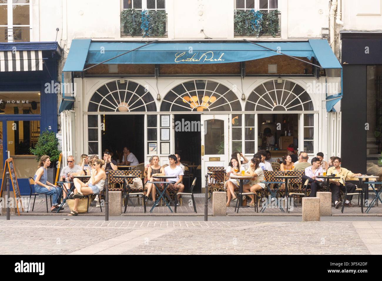 Clients assis sur la terrasse extérieure d'un café du Central Park à Paris, France. Banque D'Images