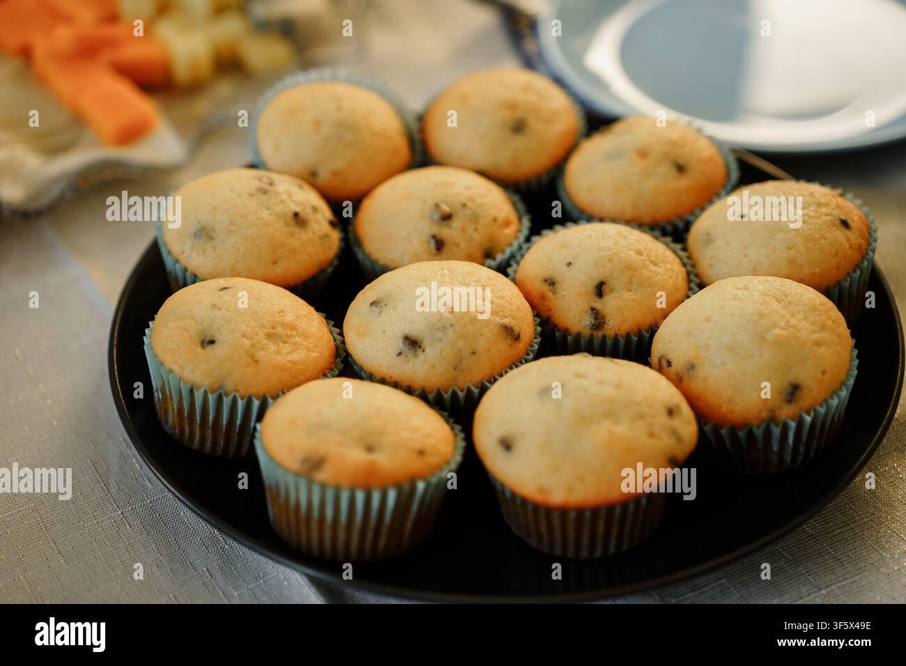 Plan en hauteur de muffins aux pépites de chocolat fraîchement cuits sur une assiette noire, mettant en valeur les textures brun doré, parfaits pour les blogs alimentaires ou les menus de café Banque D'Images