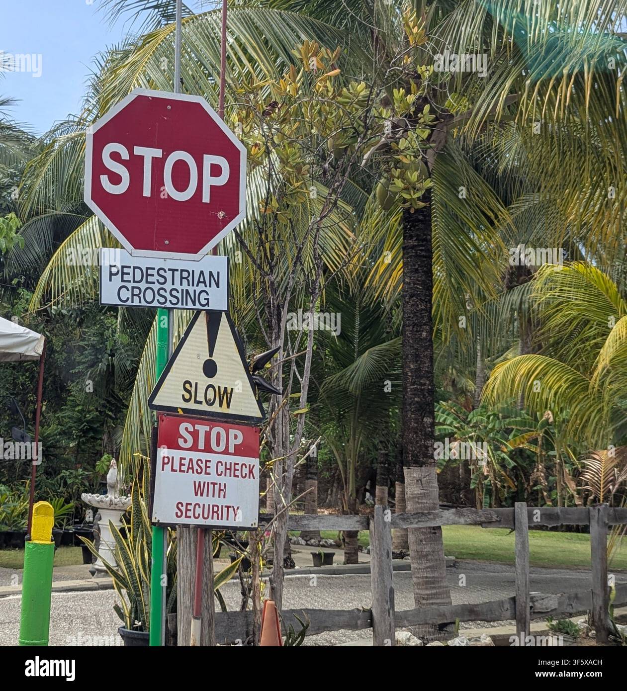 Plusieurs panneaux de signalisation indiquant arrêt, passage pour piétons, ralentir et veuillez vérifier avec la sécurité, à Trinité-et-Tobago. - Image de stock capturée avec un smartphone