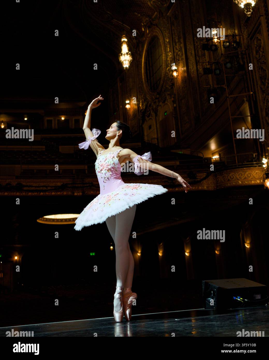 Ballerine tournoyant les bras étendus sur une large scène de théâtre Banque D'Images