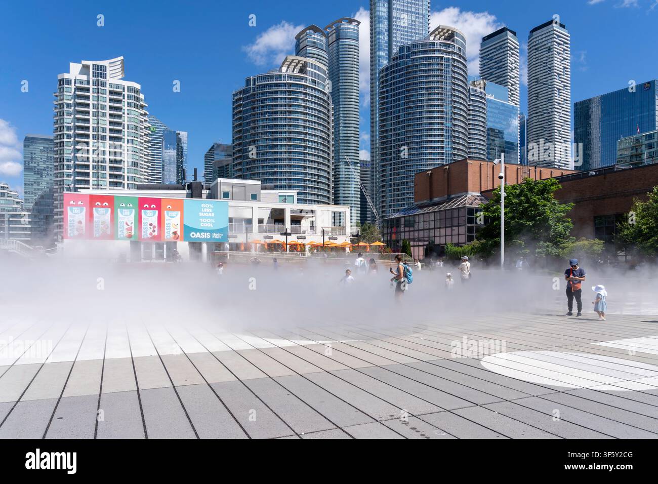 Les gens s'amusent sur la place publique dotée d'un système de brumisation au niveau du sol au Harbourfront Centre à Toronto Banque D'Images