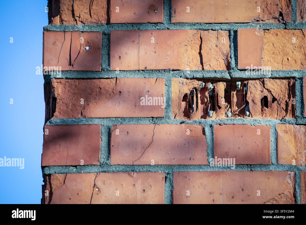 Gros plan d'un coin de mur en briques détérioré montrant des fissures, l'érosion et une surface de construction vieillie Banque D'Images