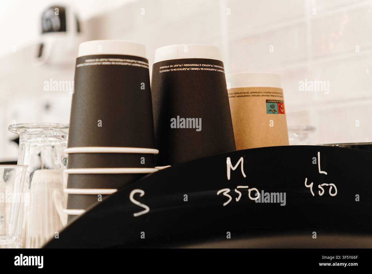Gobelets à emporter empilés disposés derrière le comptoir du café, prêts à servir des boissons chaudes. Essentiels de café dans un intérieur moderne. Banque D'Images