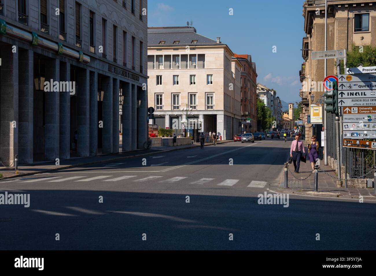Bergamo, Italie - 16 juin 2026 : Scène de rue urbaine à Bergame mettant en scène des piétons marchant devant des bâtiments en pierre contemporains et des panneaux de signalisation sur une b Banque D'Images