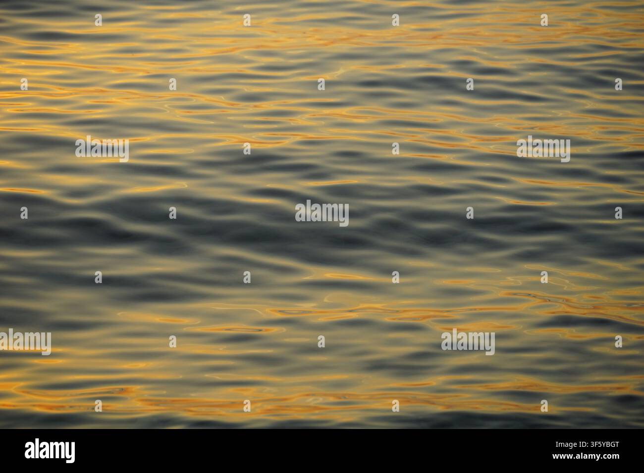 Surface de la mer avec un reflet jaune étincelant des rayons du soleil sur la surface de l'eau de mer Banque D'Images