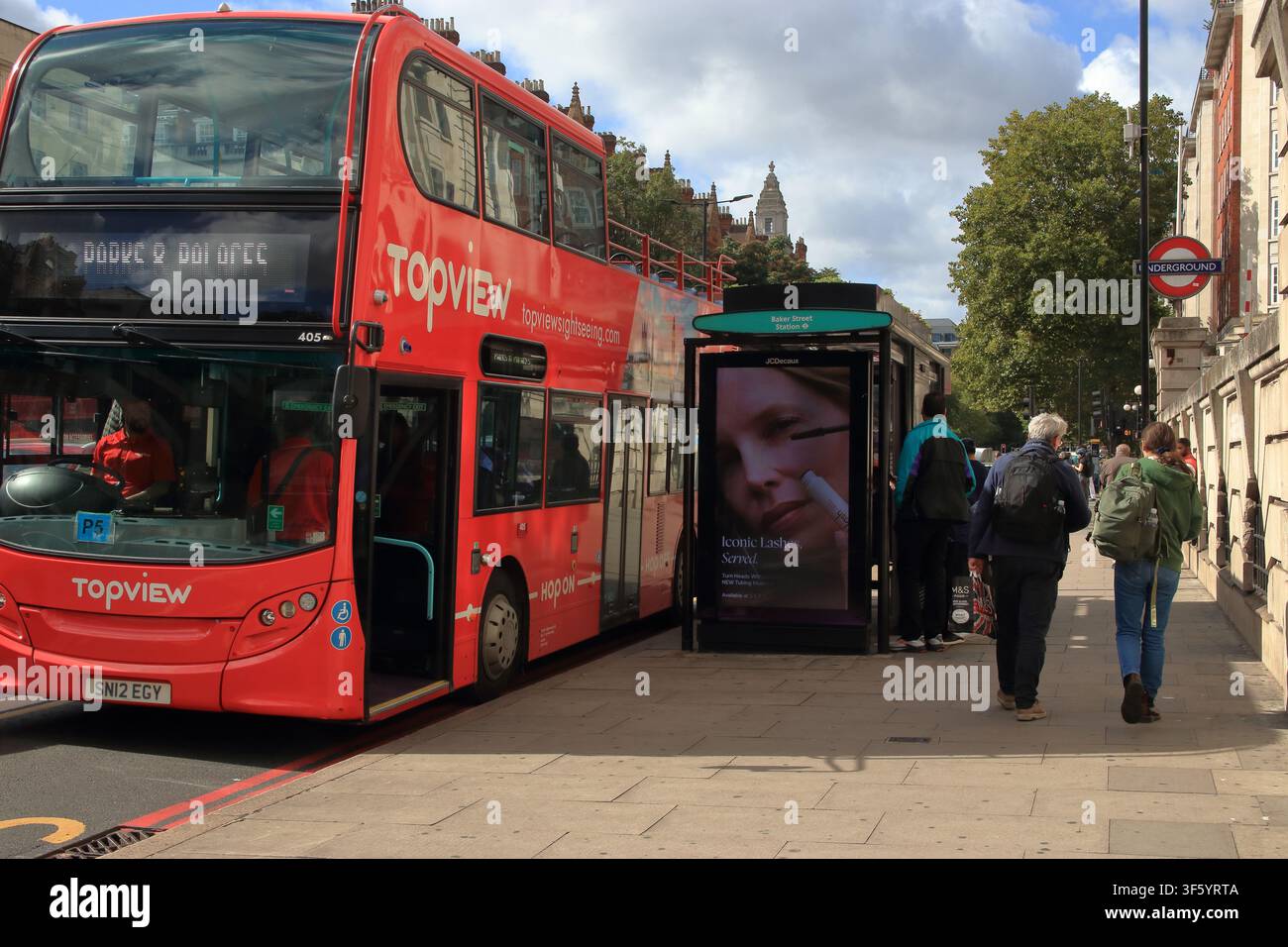 Photographie éditoriale prise à Baker Street à Londres, montrant un bus de tourisme à deux étages TopView rouge vif garé à côté d'un abribus Banque D'Images