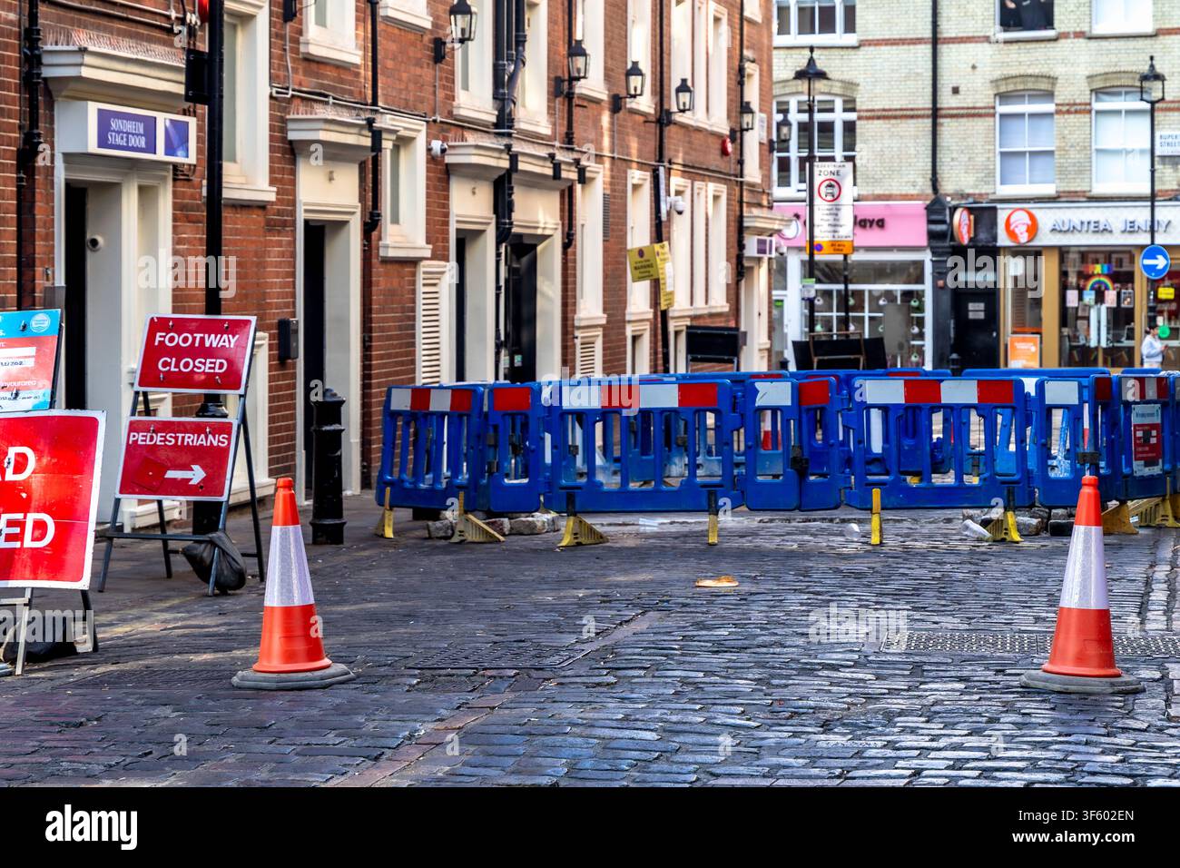 Londres, Angleterre, Royaume-Uni - 17 juillet 2026 : Travaux routiers et barrières de déviation pour piétons le long d'une rue pavée près du Sondheim Theatre Banque D'Images