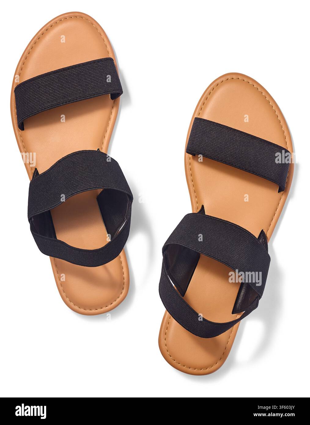 Paire de sandales pour femmes isolées sur fond blanc, sangles élastiques noires et semelles plates brun tan, chaussures d'été tendance en vue de dessus Banque D'Images