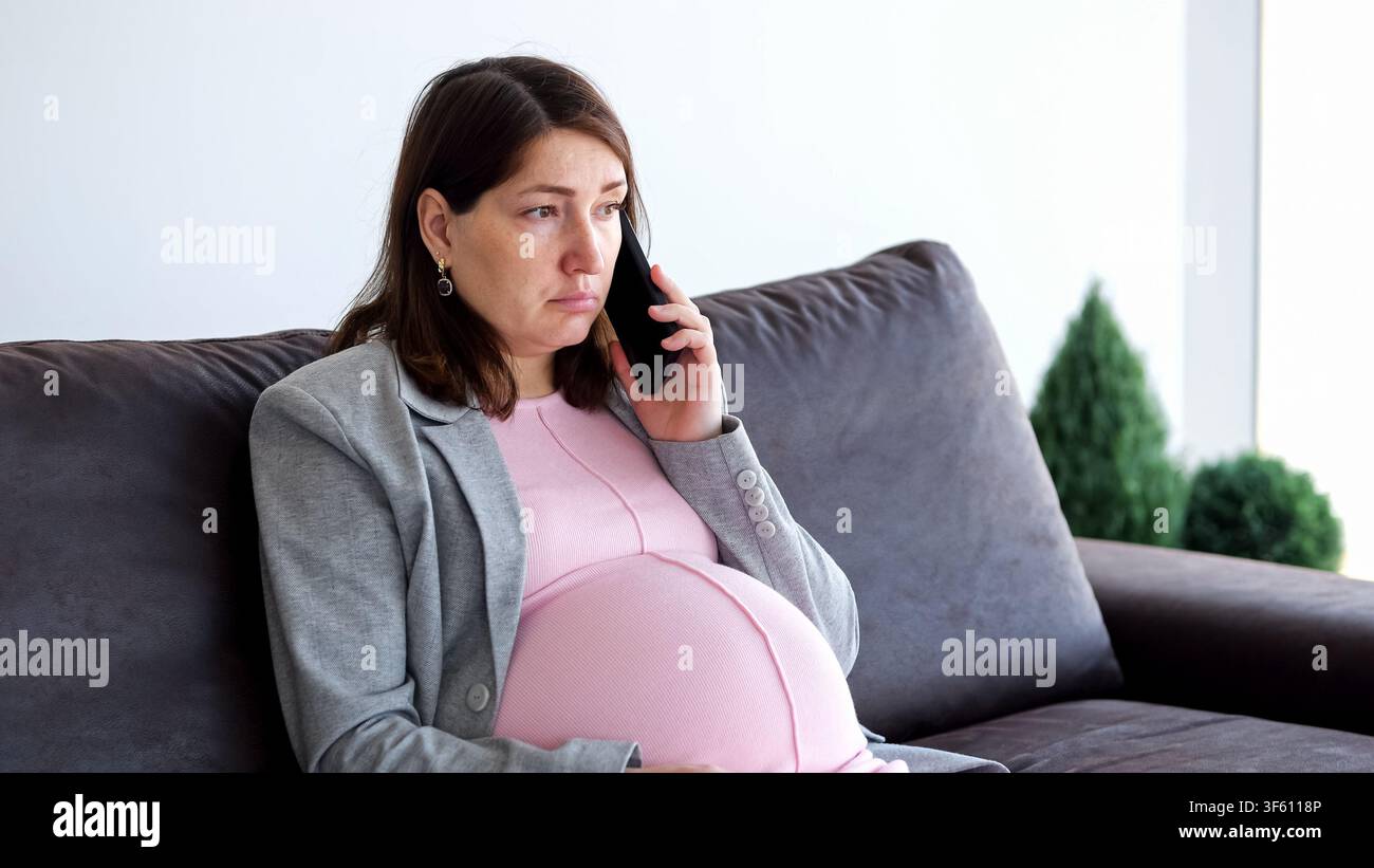 Femme enceinte en pleine conversation téléphonique émouvante tout en étant assise Banque D'Images