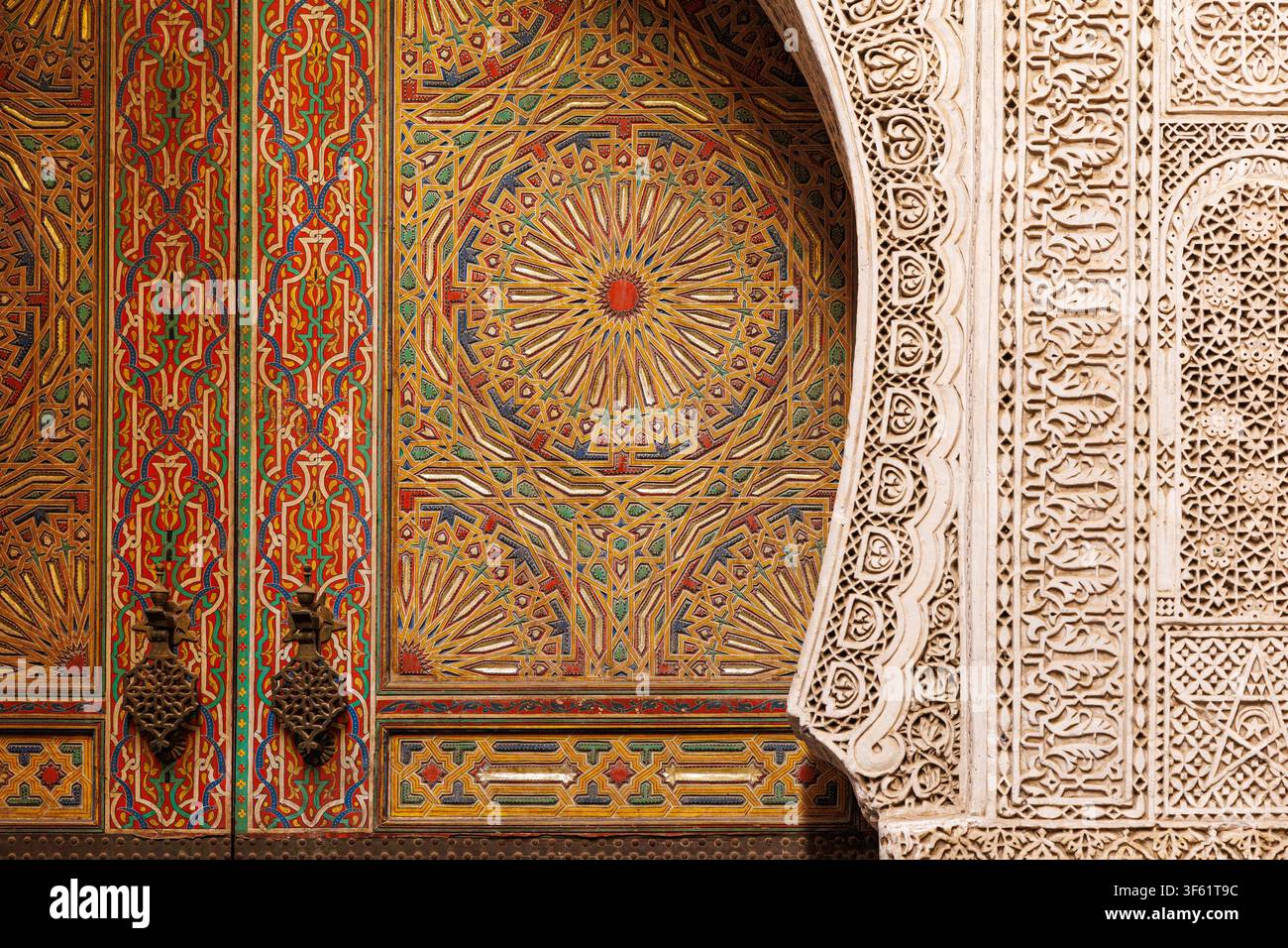 gros plan d'un panneau de porte en bois peint de manière ornée à côté d'une arche en stuc finement sculptée au Mausolée de Sidi Ahmed al-Tijani dans la médina de Fès Banque D'Images