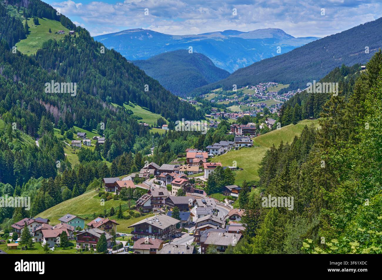 Village de montagne alpin dans une vallée verte avec des forêts denses et des sommets lointains. Banque D'Images