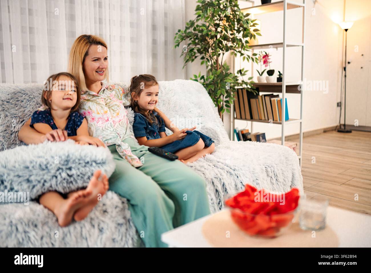 Mère et deux filles regardant la télévision à la maison Banque D'Images