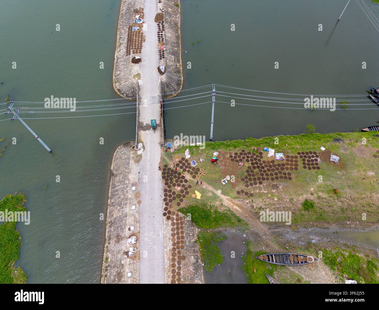 Vue aérienne de galettes de bouse de vache circulaires séchant sur le sol près d'une route rurale et d'eau à Kishoreganj, division de Dhaka, Bangladesh. Banque D'Images