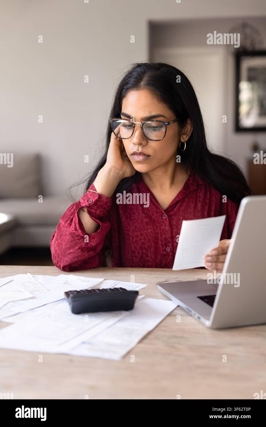 Jeune femme indienne de 25 ans gérant ses finances et vérifiant ses factures Banque D'Images